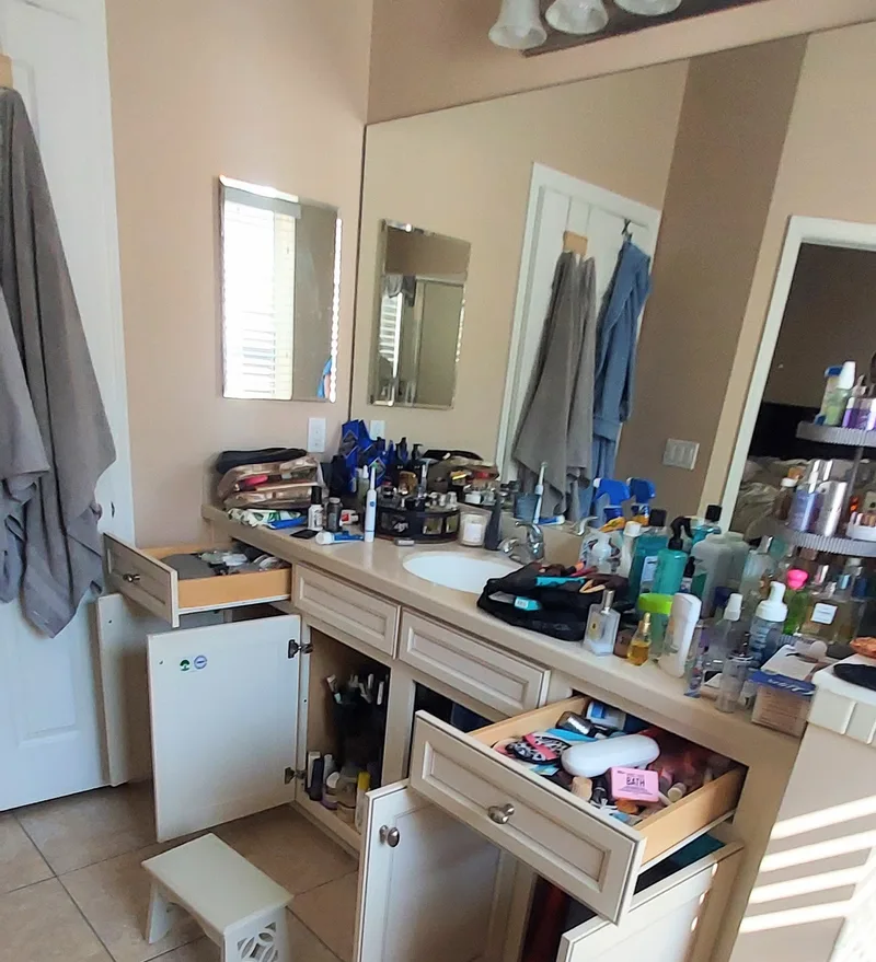 Bathroom with cabinets and counters full of toiletries 